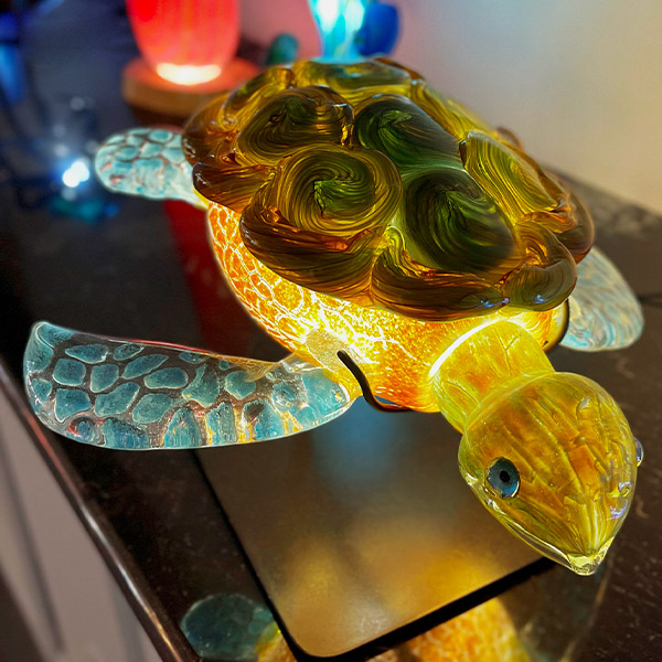<p>Murrine/Frit Crackle Honu<br>Internally Illuminated with LEDs <br>Appx. 17” long (head to tail) x 16” wide (fin to fin) x 11” tall<br> Retail Price: $13,449.00</p>
